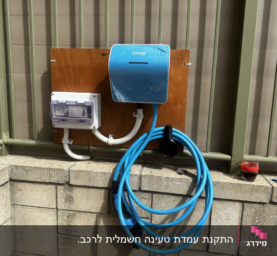 עמדת טעינה חשמלית עם כבל כחול על קיר